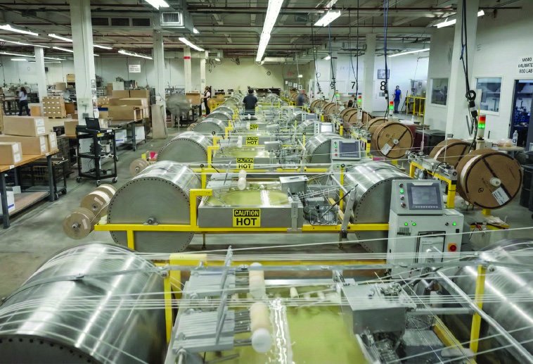 Automated candle wick production floor with waxed wick on reels.